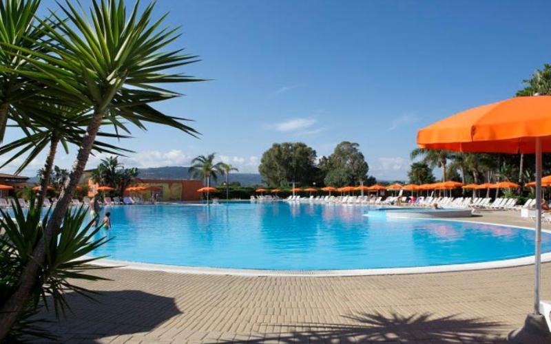 Piscina azzurra, ombrelloni arancioni, palme, atmosfera di relax e vacanza sotto il sole.